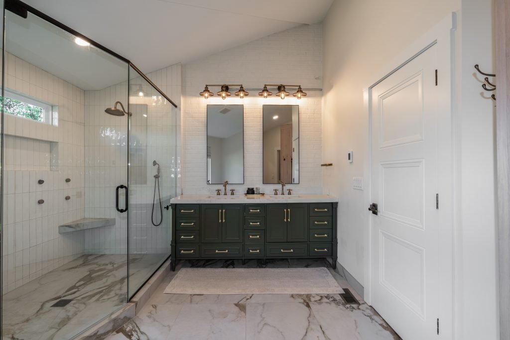 master bathroom with white tiles and a dark green vanity built by kamanski construction