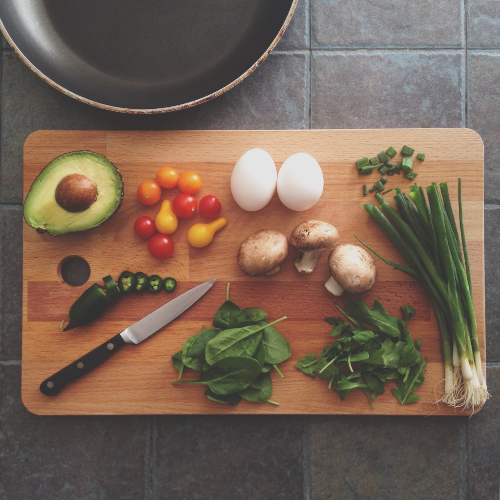 cutting board with veggies and eggs on a tile kitchen countertop